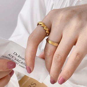 Detail of two gold rings with twisted weave and olive leaf texture on model's hand