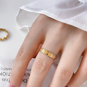 Macro shot of gold olive leaf ring with detailed feather texture on model finger