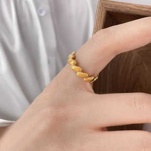 Detailed view of a gold-colored twisted metal ring with smooth polished finish on hand