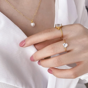 Anelli cuore in zircone dorato e collana di perle su modella con camicia di seta