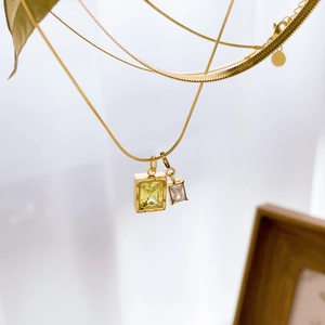 Detail einer goldenen Schlangenkette mit zwei quadratischen Zirkonia-Anhängern in Makro