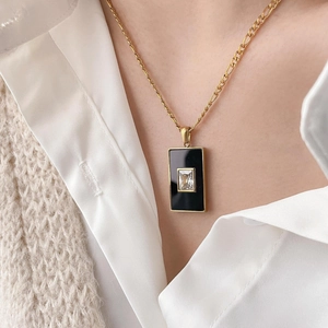 Detail einer goldenen Schlangenkette mit schwarzem Achat-Anhänger und quadratischem Zirkon