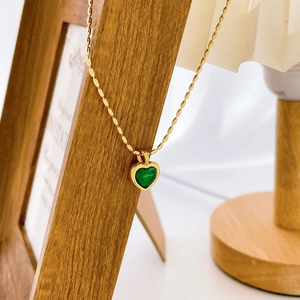 Détail d'un pendentif cœur vert élégant avec une chaîne à billes en acier doré