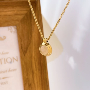 Gros plan du collier en titane plaqué or 18K avec pendentif rond en pierre œil de chat