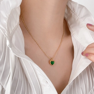 Élégant collier plaqué or 18 carats avec pendentif cœur vert porté par un mannequin