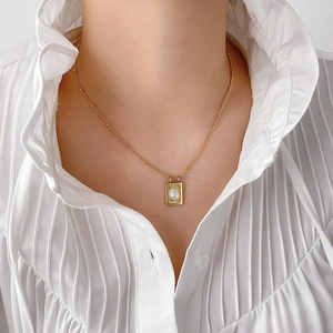 Collier en acier titane doré avec pendentif ovale blanc sur une chaîne satellite délicate