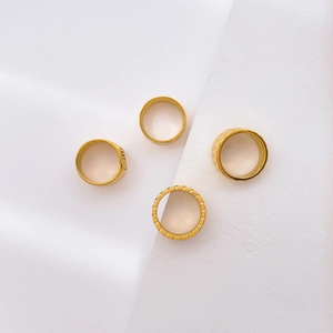 Set of four gold textured rings with geometric patterns and smooth minimalist finish