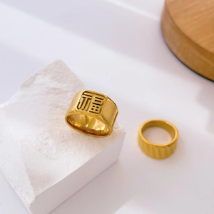 Detailed close-up of golden Fu character signet ring and textured striped band ring