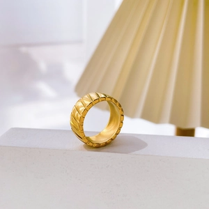 Detailed view of wide gold ring with vertical concave textures on geometric stone stand