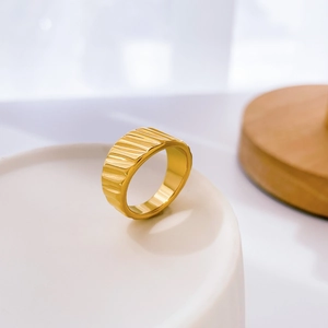 Detail of wide gold textured ring with vertical rippled pattern on ceramic tray
