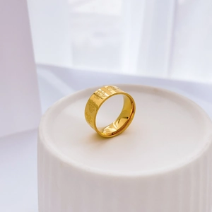 Macro shot of gold floral engraving and textured plant patterns on the wide ring band