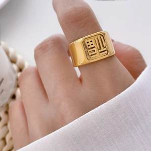 Macro shot of gold-plated wide ring featuring embossed Chinese Fu character detail
