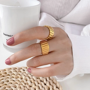 Close-up of gold vertical ribbed rings with textured grooves on person's hand