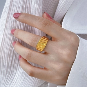 Macro shot of a chunky gold ring with a textured ribbed pattern on the finger