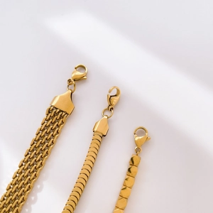 Detailed macro of three gold-plated textured chains featuring fish scale and geometric links