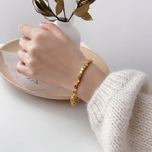 Macro shot of geometric gold bead bracelet with fish scale chain on a model wrist
