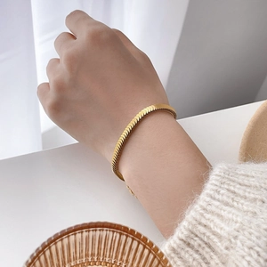 Detail of vintage gold fish scale bracelet on wrist with elegant knitwear