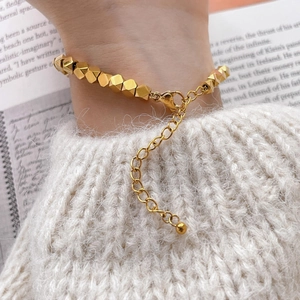 Detailed close-up of gold geometric bead bracelet with lobster clasp and extension chain