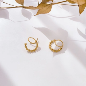 Detailed view of gold C-shaped earrings with bead accents and double ring geometric design