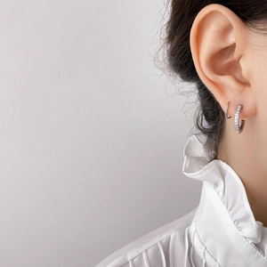 Irregular C-shaped bead earrings with zircon pavé setting shown on model's ear