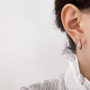 Close-up of minimalist silver C-shaped earrings with micro-set cubic zirconia on model