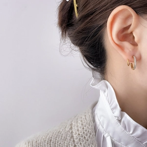 Elegant gold geometric C-shaped hoop earrings with micro-paved cubic zirconia worn by model