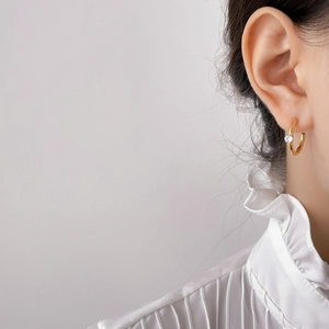 Close-up of gold-plated irregular C-shaped earrings with micro-pave cubic zirconia