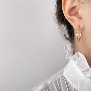Detailed view of gold-plated C-shaped earrings with zircon inlay worn by a model