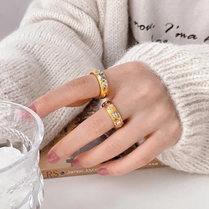 Detail of wide gold rings with irregular zircon stones worn by a hand model