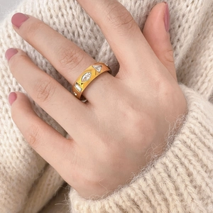 Detailed view of wide gold-finished ring with assorted shaped zircon stones on a hand