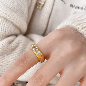 Detail of a wide gold-plated ring featuring three inset oval zircon stones on a model