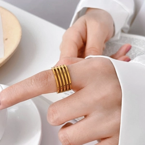 Détail d'une large bague dorée multicouche portée à l'index dans un décor de style de vie