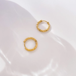 Detail shot of golden hoop earrings with hammered metal texture on white background