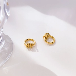 Detail view of gold hoop earrings with three movable beads on a minimalist background