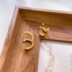 Detail of chunky gold hoop earrings on wooden tray with polished hammered texture finish