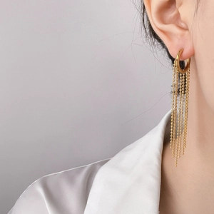 Detail of gold circle earrings with layered beaded tassel chains on a model
