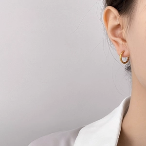 Detail of gold hammered hoop earring showing textured finish on female model ear