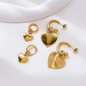 Close-up of gold heart earrings with zircon inlay and sunburst textured metal finish