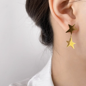 Close-up of elegant double layered gold star earrings worn on ear with metallic finish
