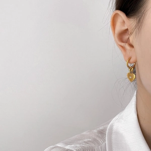 Elegant gold-plated heart pendant hoop earrings with small zircon on a female model
