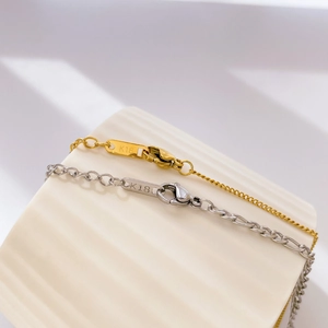 Detail of lobster clasp and K18 hallmark on gold and silver checkered pendant necklaces