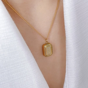 Close-up of golden checkered pendant necklace with cubic zirconia on a model's neck
