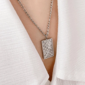 Close-up of a silver checkerboard zircon rectangular pendant necklace on a model