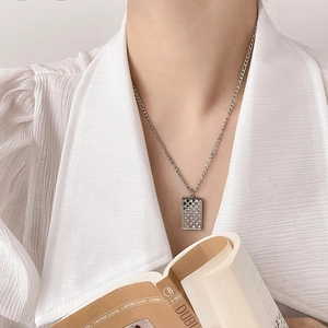 Macro detail of silver rectangle checkerboard pendant with cubic zirconia on model