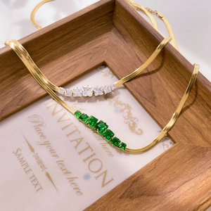 Detail of 18K gold plated snake bone chains with square zircon and emerald green stones