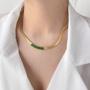 Detail of flat gold snake chain necklace featuring inlaid green rectangular zircon stones