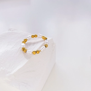 Détail macro de perles plaquées or 18 carats et perles baroques sur fond de pierre blanche