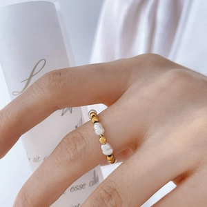 Détail d'une bague perlée avec perles blanches irrégulières et billes en acier doré 18K