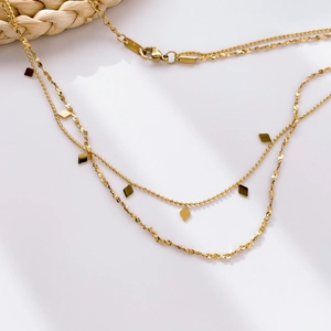 Detail of layered gold snake chain necklace with mini moon pin and diamond pendants