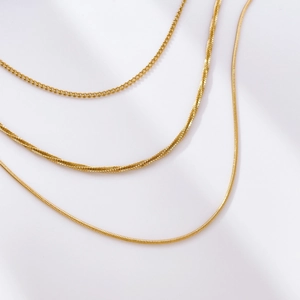 Close-up of golden curb, herringbone, and snake chain textures on white background